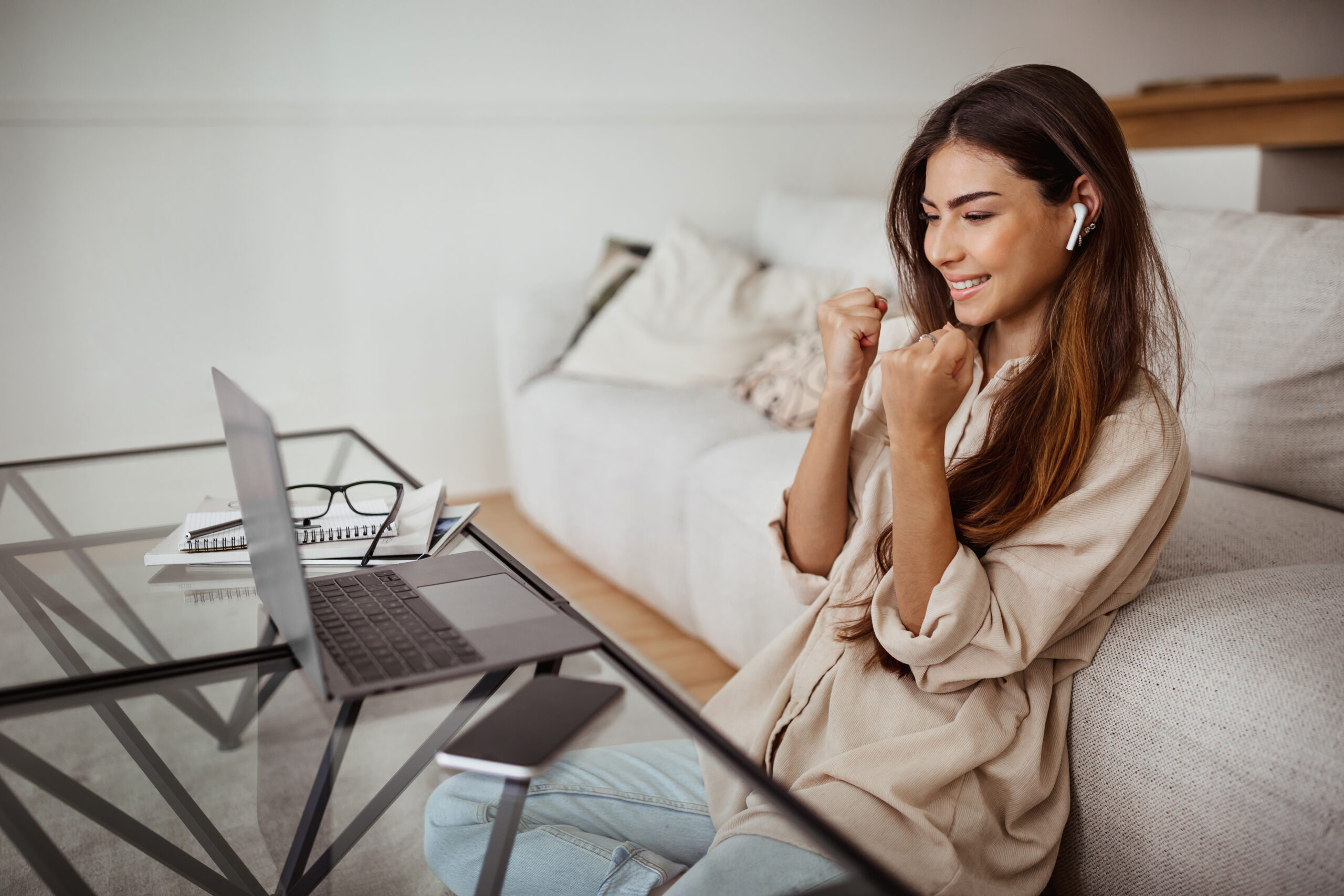 Cheerful millennial mixed race lady in glasses and wireless headphones has video call on laptop