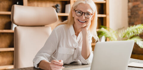 Freelancer teacher doing paperwork, signing contracts, documents while working on laptop in office