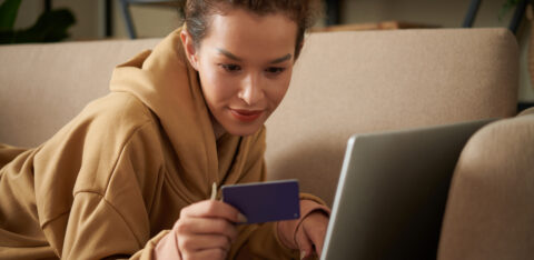 woman looking at a credit card while using her laptop