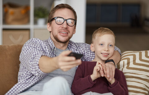 Father watching educational TV shows with son