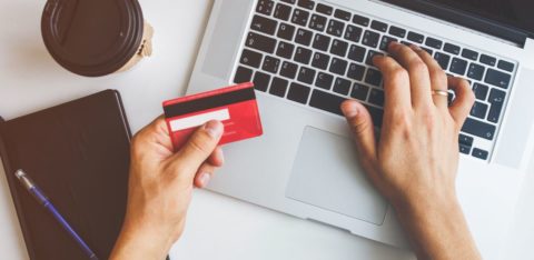 person holding a credit card in front of a laptop