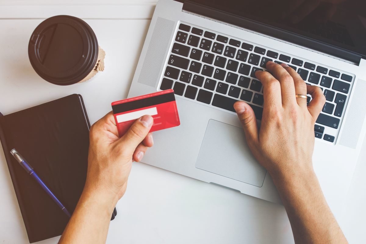 person holding a credit card in front of a laptop