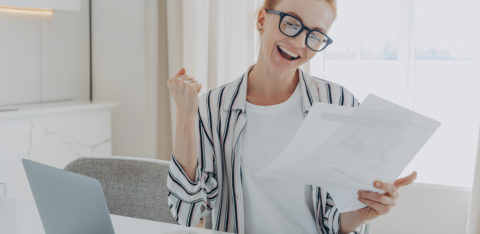 overjoyed redhead woman celebrating getting a bigger paycheck or tax refund