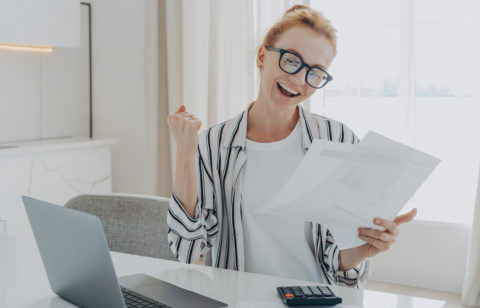 overjoyed redhead woman celebrating getting a bigger paycheck or tax refund