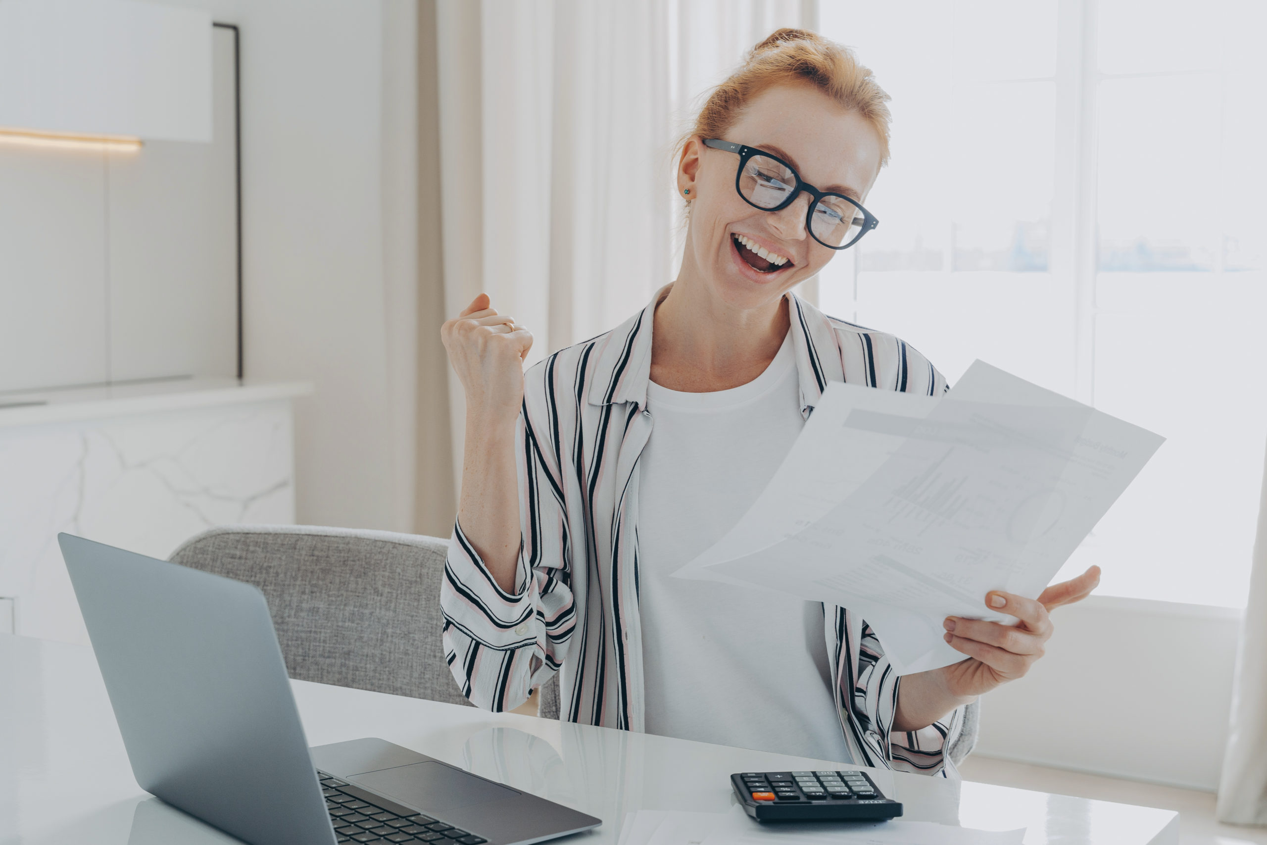 overjoyed redhead woman celebrating getting a bigger paycheck or tax refund