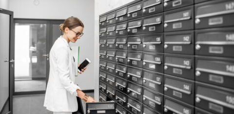 Woman opening mailbox at the residential building hall