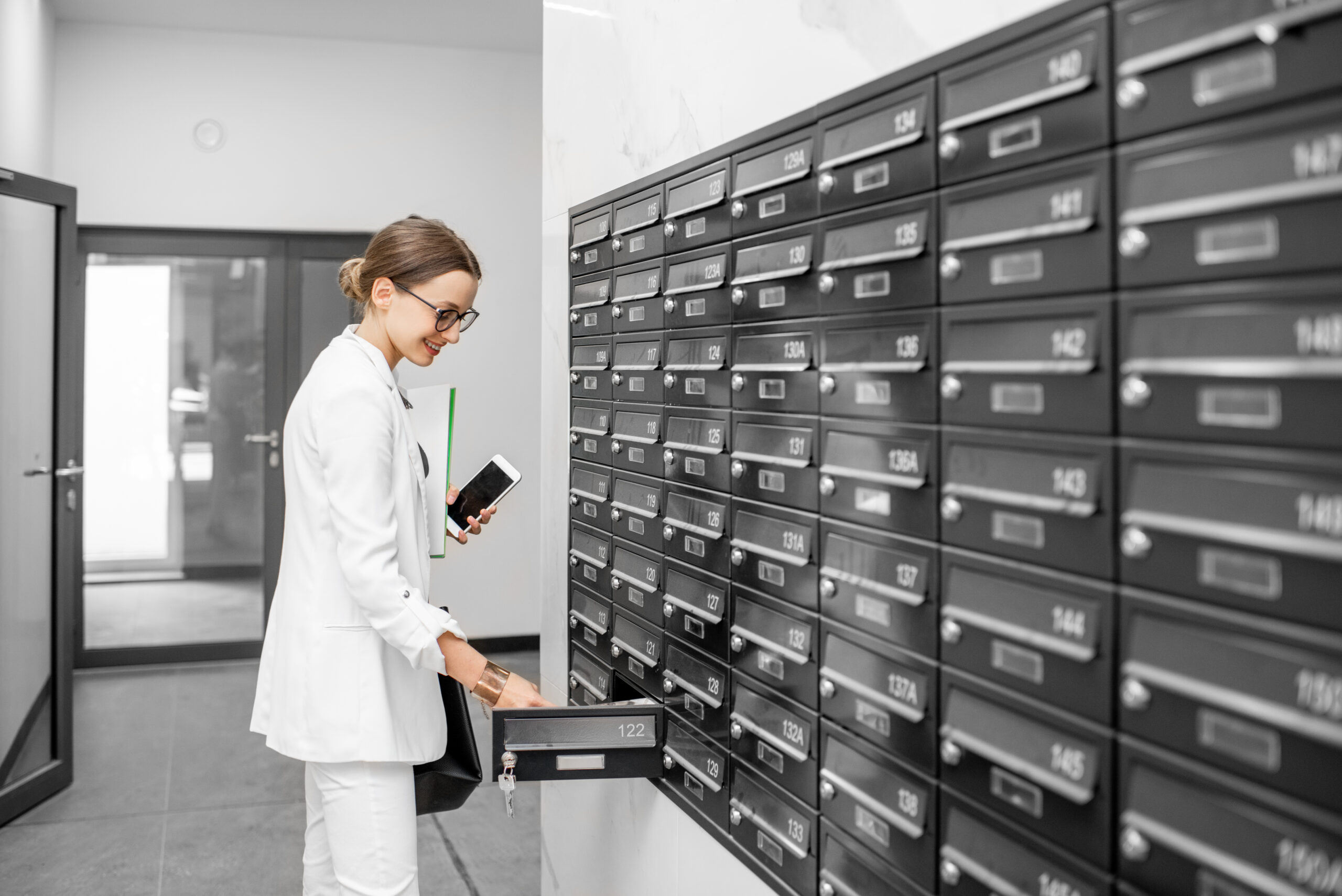 Woman opening mailbox at the residential building hall