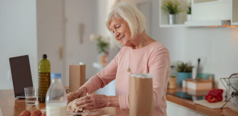 Smiling retired woman cooking while on a money diet