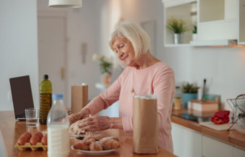 Smiling retired woman cooking while on a money diet