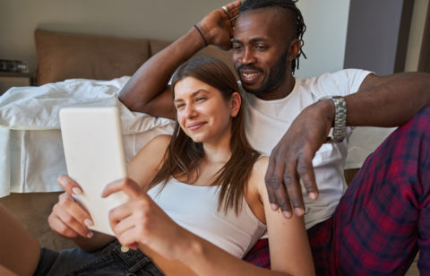 happy couple watching something on tablet