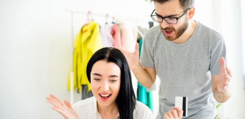 couple arguing at computer over spouse being bad with money