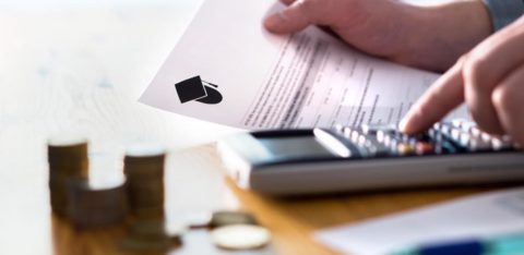 person reading student loan paperwork while using a calculator