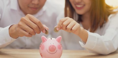 couple putting coins in a piggy bank to reach savings goals