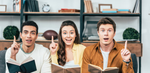 three people holding books