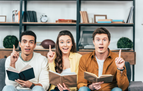 three people holding books