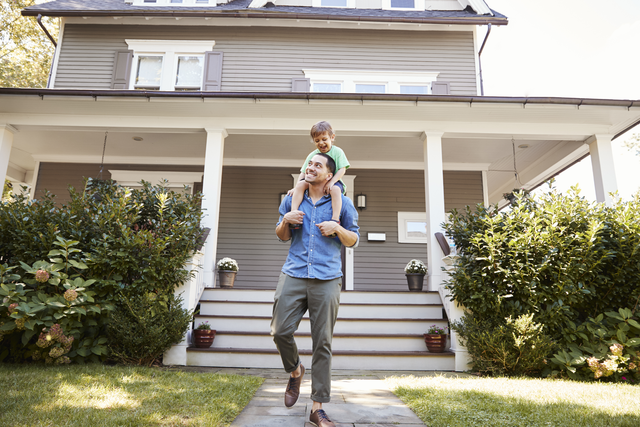 Father Giving son ride on shoulders outside home