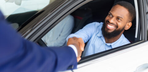 Man Sitting Inside Of New Car And Shaking Hands With Salesman