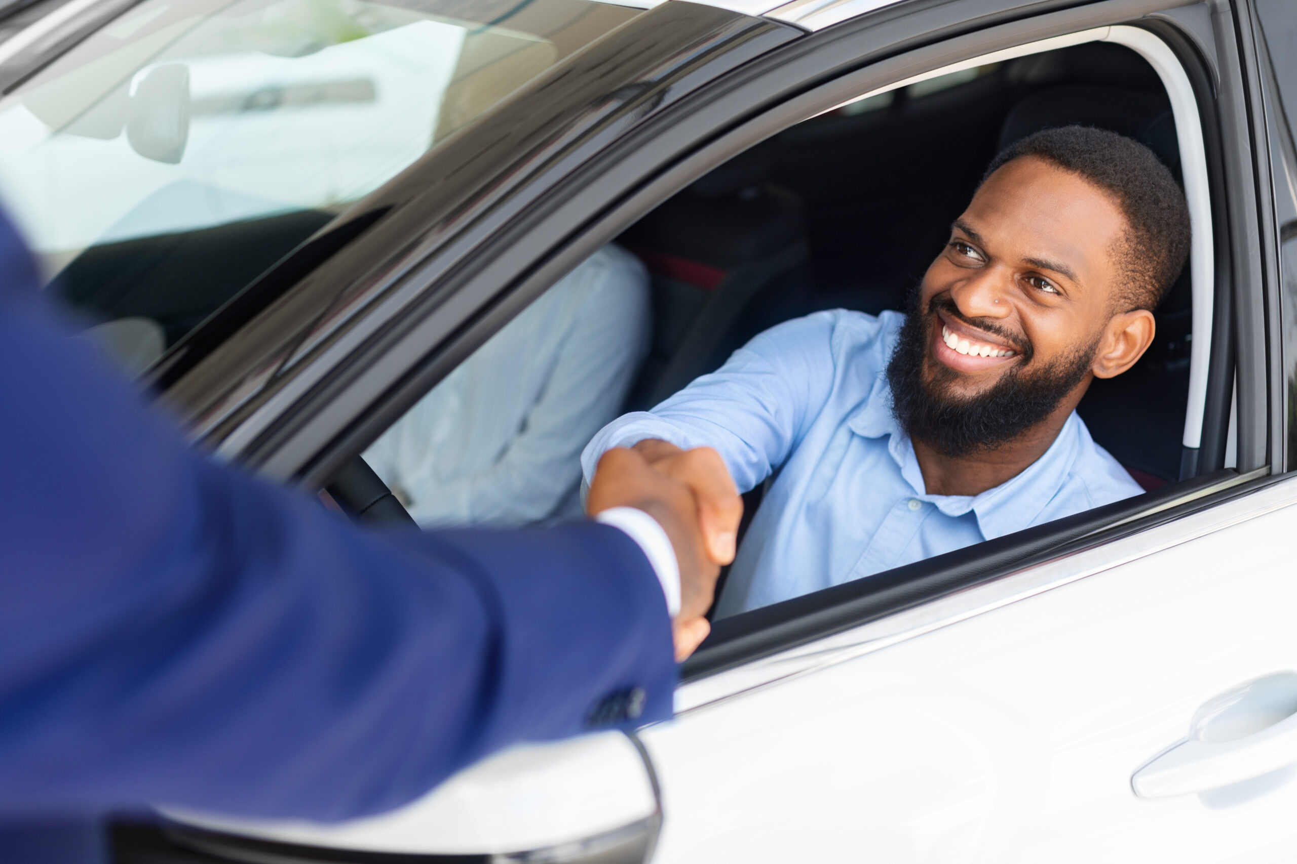 Man Sitting Inside Of New Car And Shaking Hands With Salesman