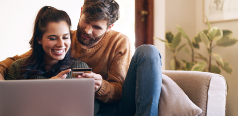 Couple looking at a credit card behind a computer