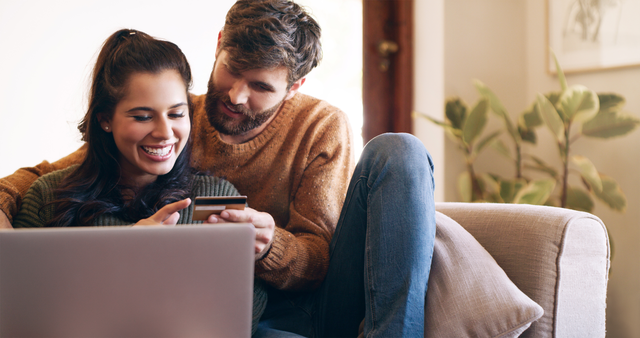 Couple looking at a credit card behind a computer