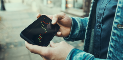 Man looking at his phone to do trading and investing