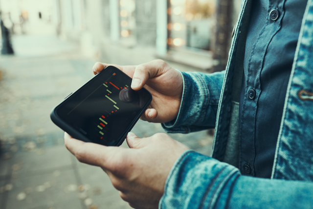 Man looking at his phone to do trading and investing