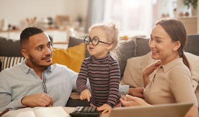 A Man and Wife look at their daugther playing with calculator