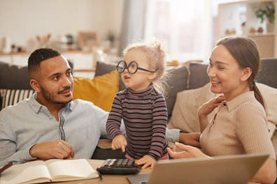 A Man and Wife look at their daugther playing with calculator