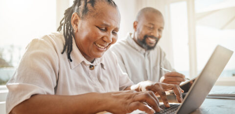 Senior couple looking at computer and filling out notepad