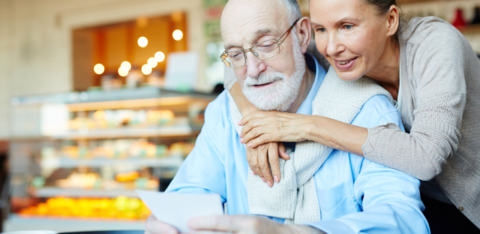 affectionate older couple looking at a note in a cafe