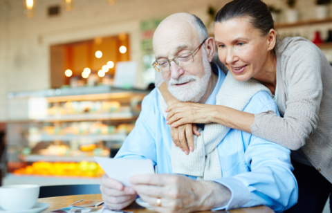 affectionate older couple looking at a note in a cafe