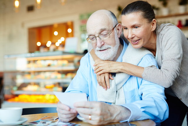 affectionate older couple looking at a note in a cafe