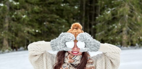 winter portrait of a young woman holding snowballs