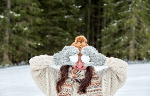 winter portrait of a young woman holding snowballs