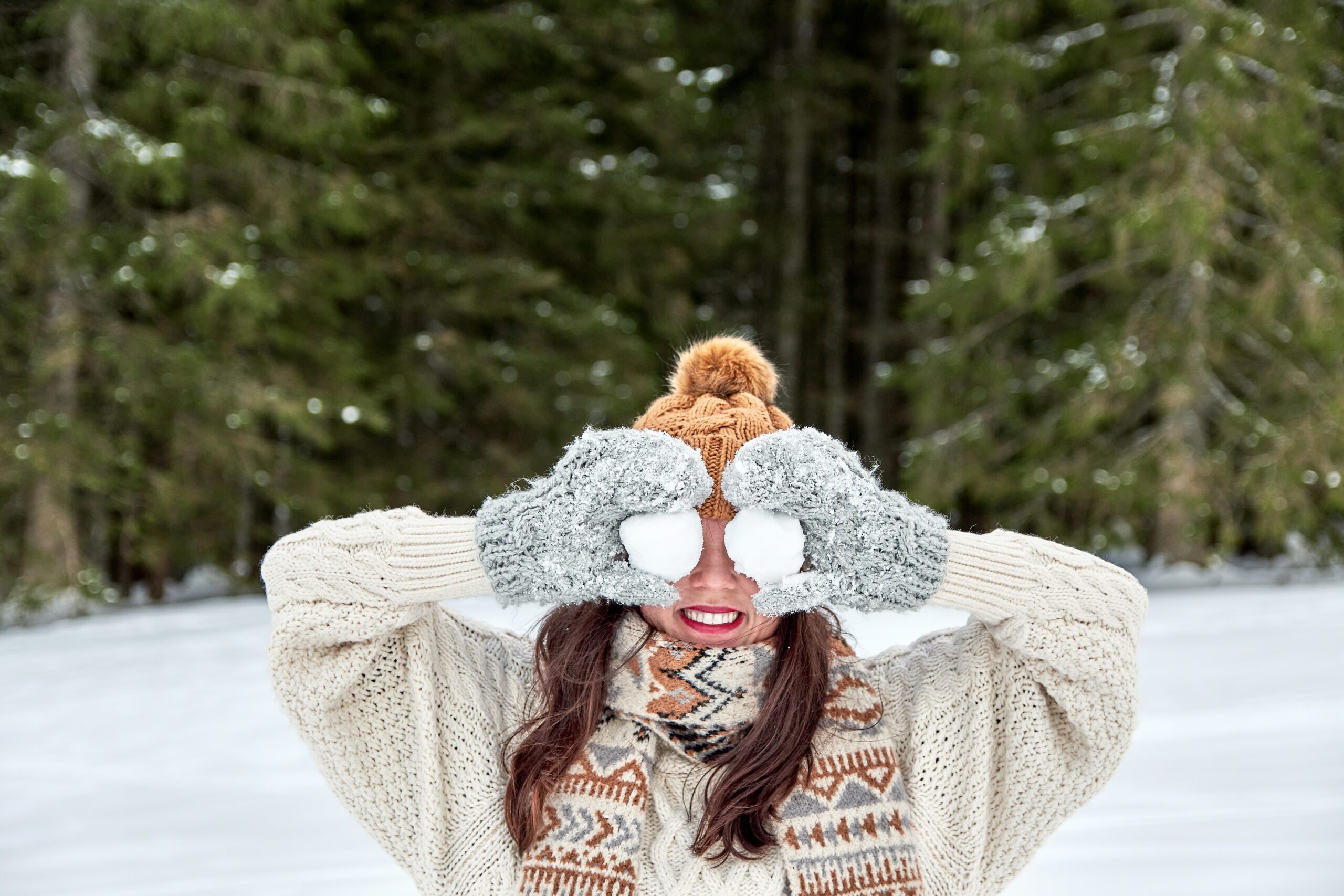 winter portrait of a young woman holding snowballs