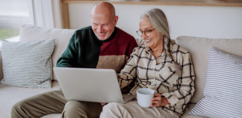 Senior couple sitting on sofa and shopping online with laptop.