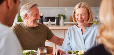 Family With Senior Parents And Adult Offspring Eating Meal Around Table At Home Together