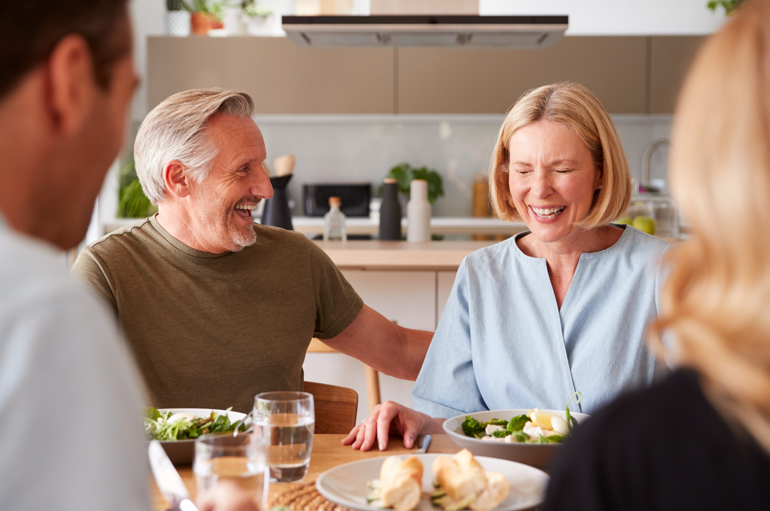 Family With Senior Parents And Adult Offspring Eating Meal Around Table At Home Together