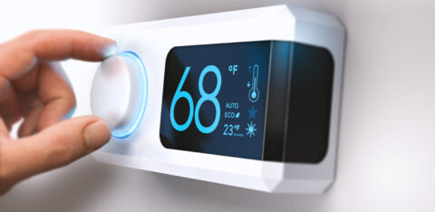 hand turning down temperature for home energy savings