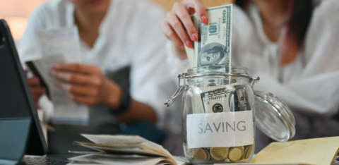 young couple putting money into a savings jar.