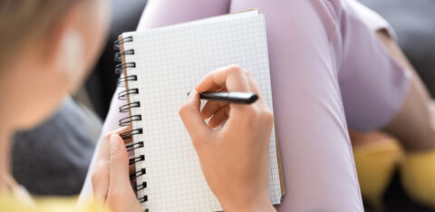 selective focus of woman writing in empty textbook