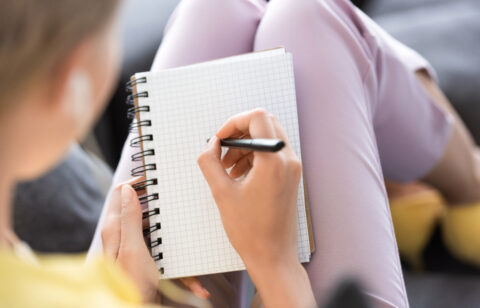 selective focus of woman writing in empty textbook