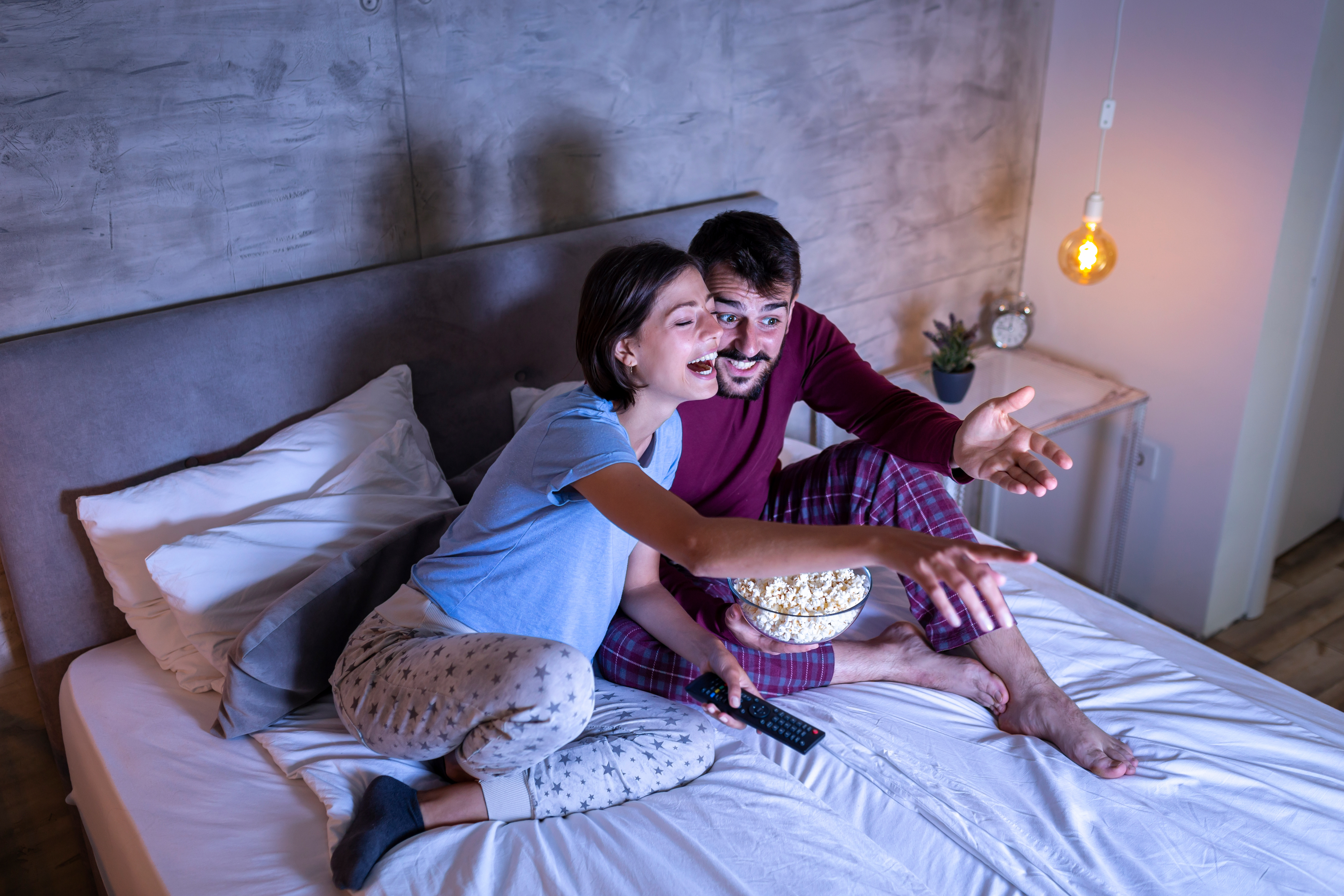 Couple watching a movie and eating popcorn in bed