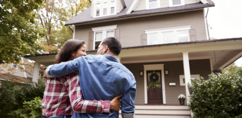 Man and woman in front of recently purchased home