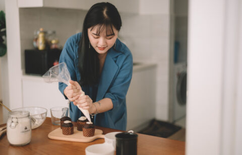 Asian Chinese female piping frosting on cupcake