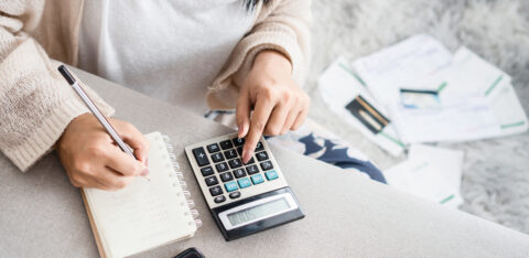 Woman looking at finances with calculator and notepad